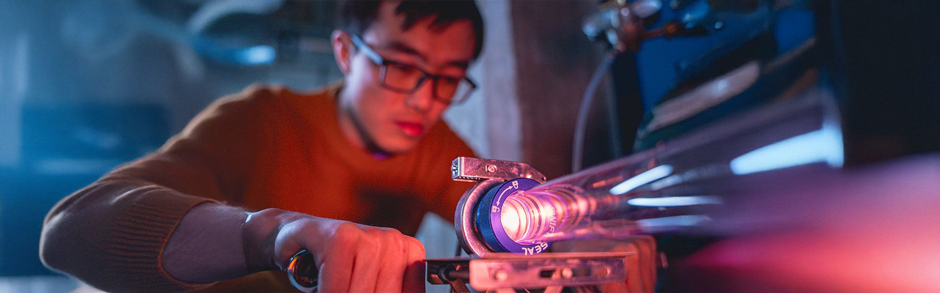 A focused man uses a torch while working on a machine, demonstrating skill and attention to detail in his task.